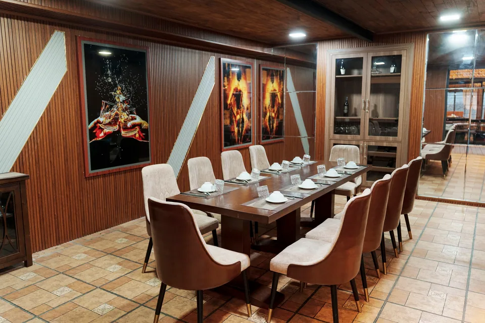 Phòng VIP ốp gỗ với tranh nghệ thuật khổ lớn, ghế nệm be và bàn dài đã chuẩn bị sẵn bát đĩa.