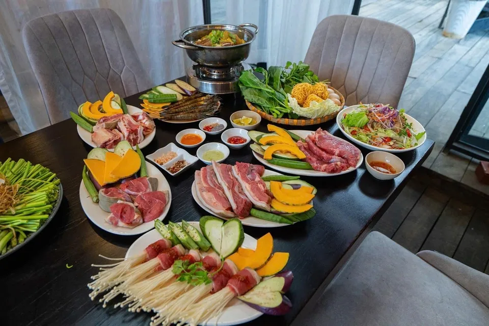 Set bàn bò tơ Bách Tùng An — lẩu nóng giữa bàn, đĩa bò tơ tươi, nấm kim châm và rau rừng Đà Lạt bày đầy.